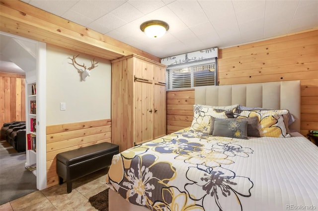 bedroom featuring light tile patterned floors and wooden walls