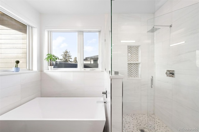 bathroom with a healthy amount of sunlight and separate shower and tub