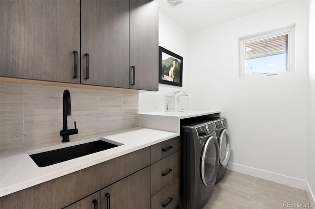 laundry room with sink, washing machine and dryer, cabinets, and light tile patterned flooring