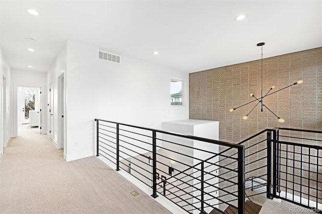 hall with plenty of natural light, light carpet, and a notable chandelier