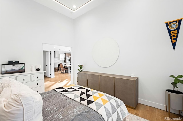 bedroom with a towering ceiling and light hardwood / wood-style floors