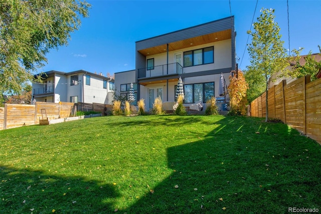 rear view of house with a balcony and a lawn