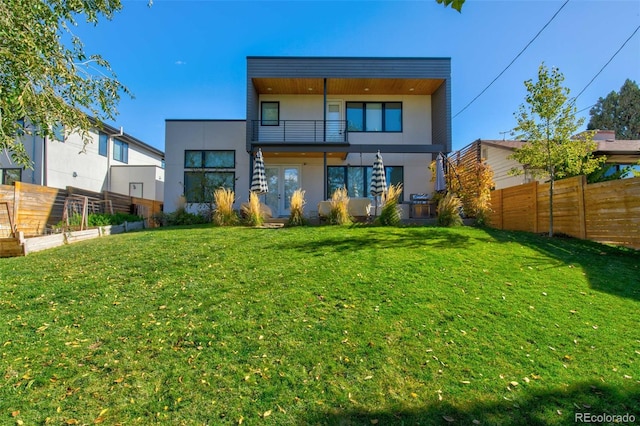 rear view of house featuring a balcony and a lawn