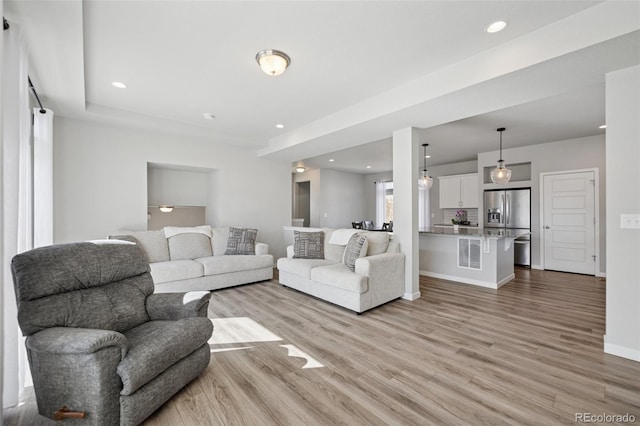 living room featuring light wood-style floors, baseboards, and recessed lighting