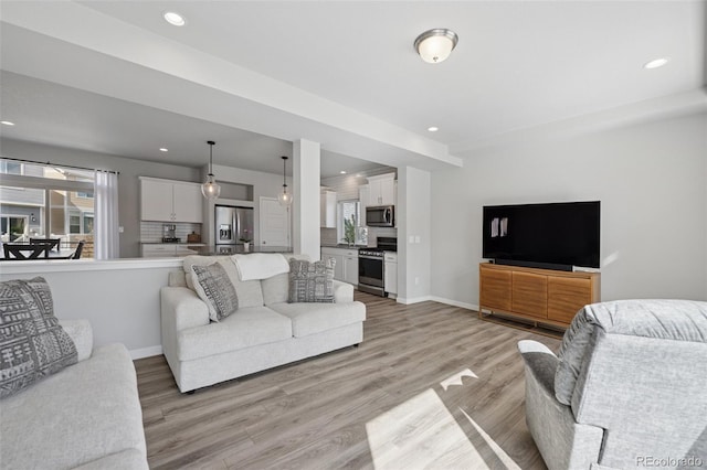 living room with recessed lighting, baseboards, and light wood-style flooring