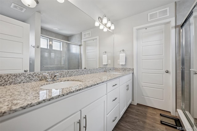 full bathroom featuring visible vents, a sink, a stall shower, and double vanity