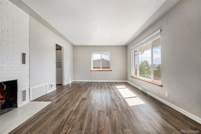 unfurnished living room with a brick fireplace and dark hardwood / wood-style flooring