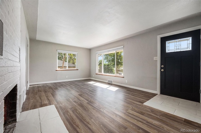 entryway featuring dark hardwood / wood-style flooring, a brick fireplace, and a textured ceiling