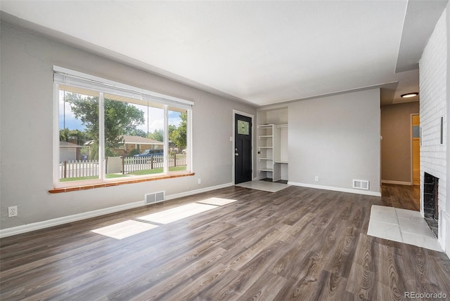 unfurnished living room with dark wood-type flooring and a fireplace