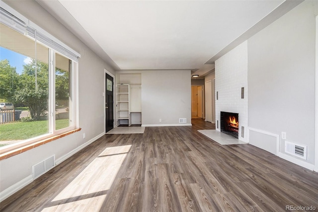 unfurnished living room featuring a fireplace, a healthy amount of sunlight, and dark hardwood / wood-style flooring