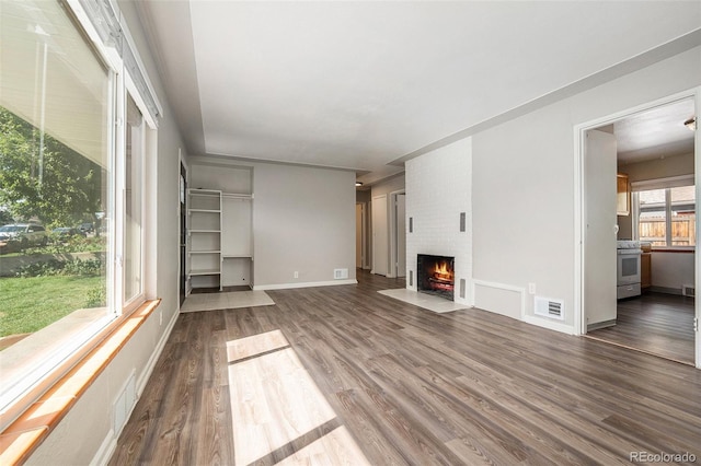 unfurnished living room with dark hardwood / wood-style flooring and a brick fireplace