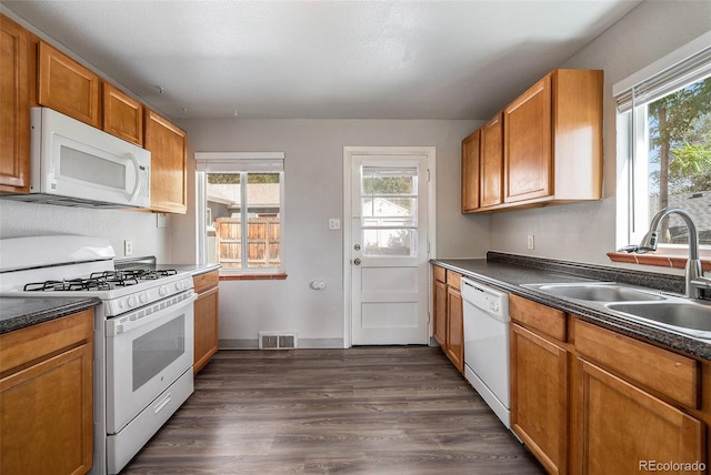 kitchen with dark wood-type flooring, white appliances, and sink