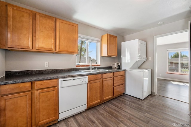 kitchen featuring sink, dark hardwood / wood-style floors, stacked washer and clothes dryer, and dishwasher