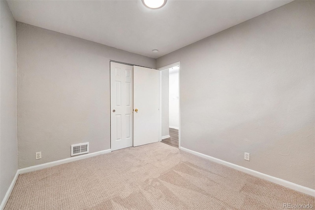 unfurnished bedroom with light carpet and a closet