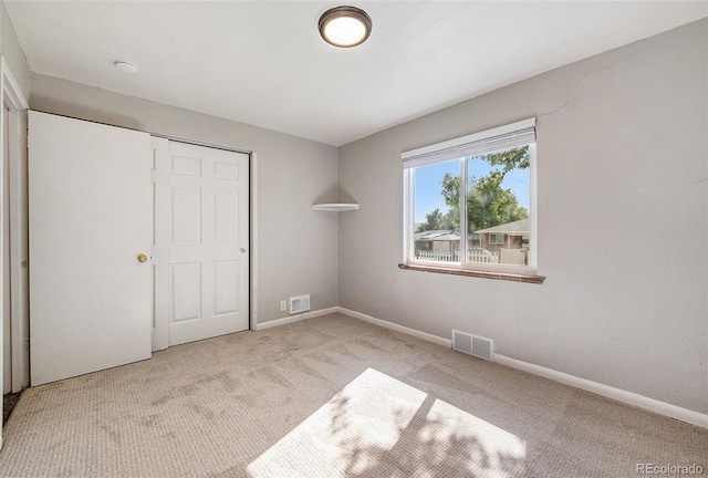 unfurnished bedroom with light carpet and a closet