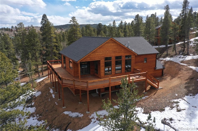 snow covered back of property with a wooden deck