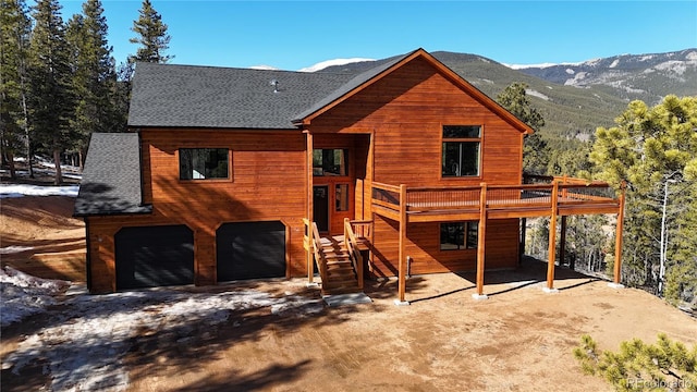 rear view of house featuring a garage and a deck with mountain view