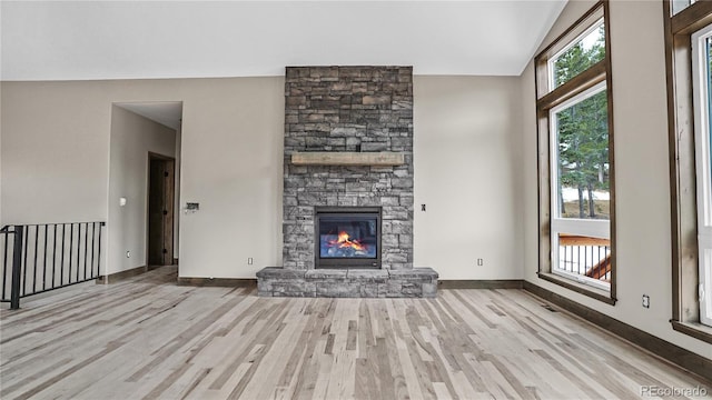 unfurnished living room with a stone fireplace and light hardwood / wood-style floors