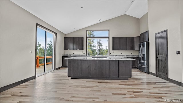 kitchen featuring dark brown cabinets, stainless steel fridge, a center island, and light wood-type flooring