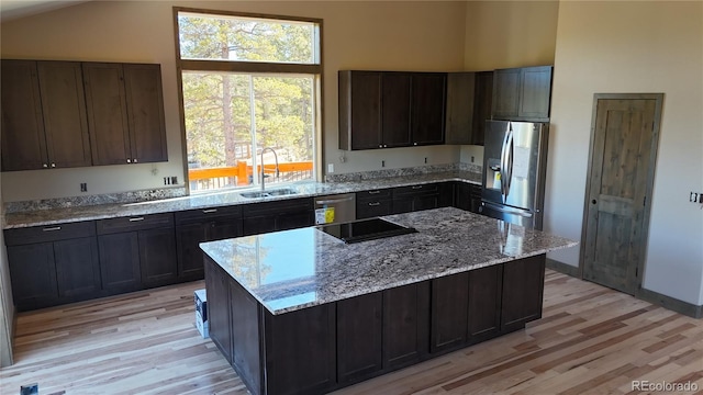 kitchen with dark brown cabinetry, stainless steel appliances, a center island, and sink