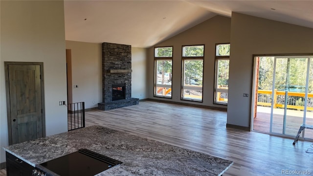 unfurnished living room with high vaulted ceiling, plenty of natural light, a fireplace, and hardwood / wood-style floors