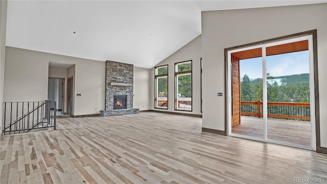 unfurnished living room with high vaulted ceiling, a fireplace, and light hardwood / wood-style floors