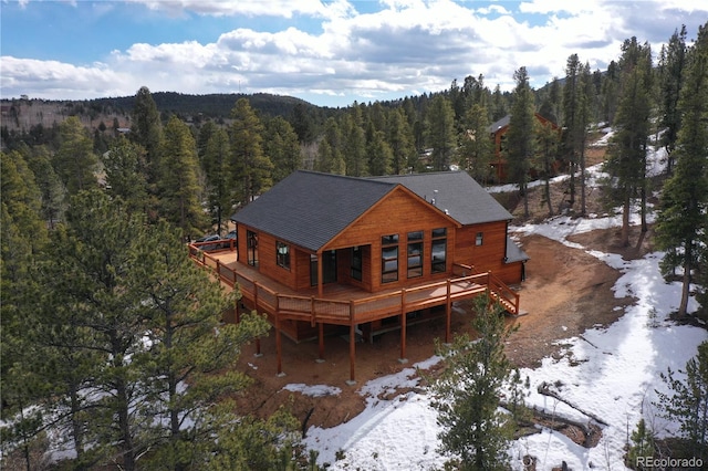 snow covered rear of property featuring a deck