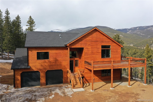 rear view of house with a garage and a deck with mountain view