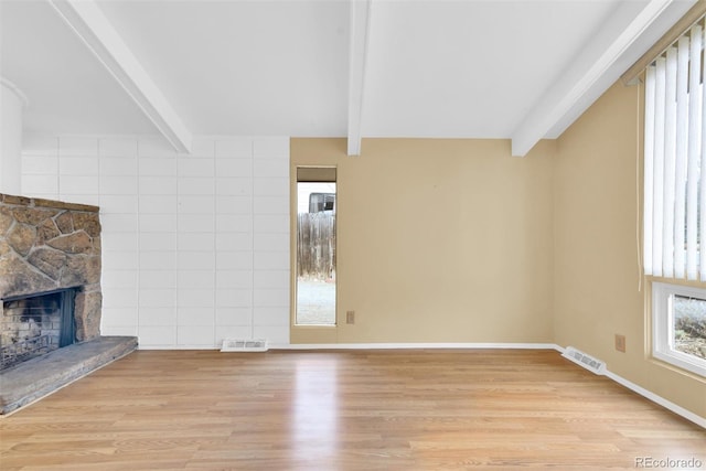 unfurnished living room featuring beam ceiling, visible vents, light wood-style flooring, and a fireplace