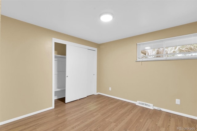 unfurnished bedroom featuring light wood-type flooring, visible vents, baseboards, and a closet