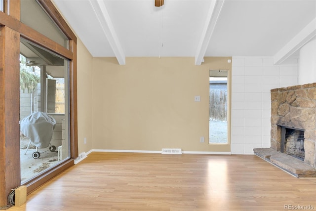 unfurnished living room featuring visible vents, beam ceiling, and a healthy amount of sunlight