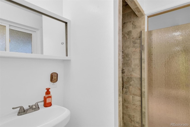 bathroom with a sink and a tile shower