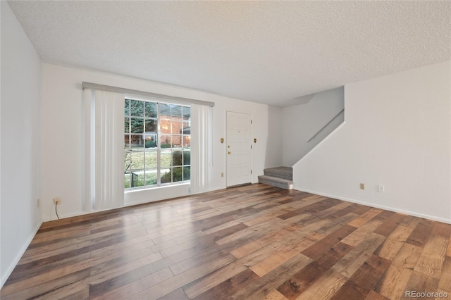 unfurnished room with a textured ceiling and dark hardwood / wood-style floors