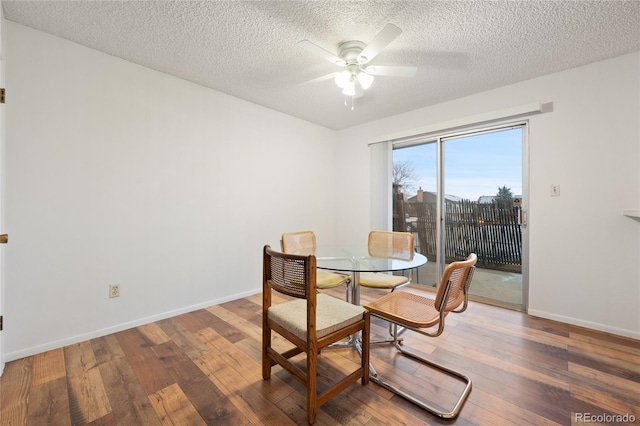 dining space with ceiling fan, dark wood-type flooring, and a textured ceiling