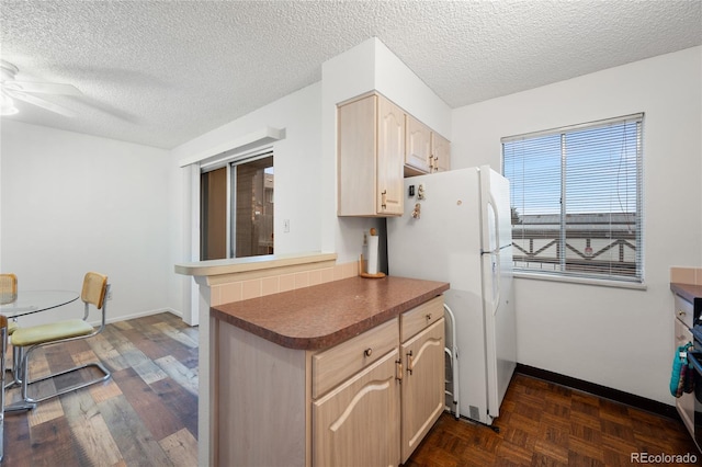 kitchen with light brown cabinets, a textured ceiling, white refrigerator, and ceiling fan