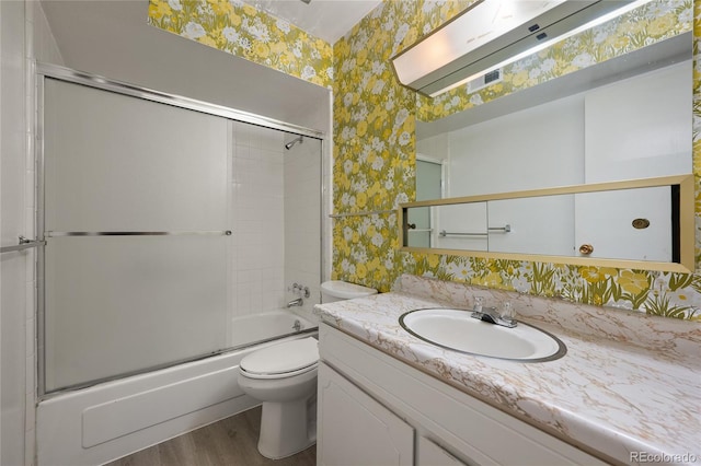 full bathroom featuring vanity, toilet, combined bath / shower with glass door, and hardwood / wood-style flooring