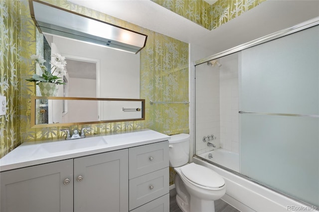 full bathroom with enclosed tub / shower combo, vanity, and toilet