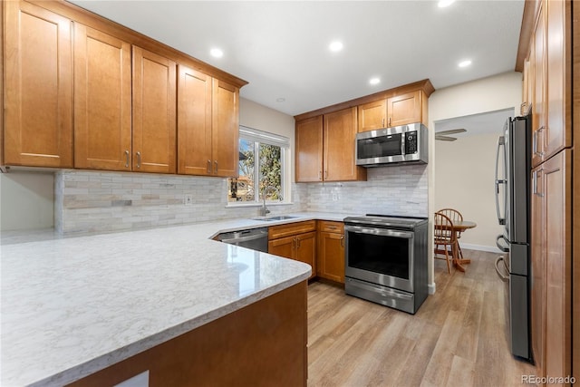 kitchen with light stone countertops, recessed lighting, decorative backsplash, appliances with stainless steel finishes, and light wood-type flooring