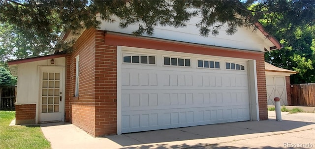 garage featuring driveway and fence