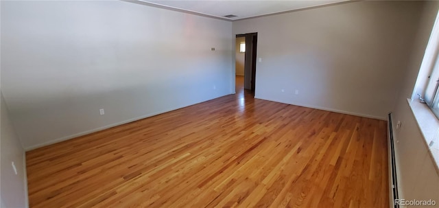 empty room featuring light wood-style flooring, crown molding, and baseboards