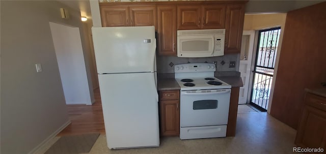 kitchen with baseboards, white appliances, and brown cabinetry