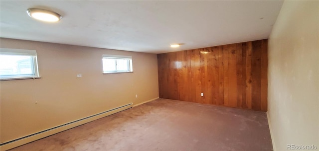 below grade area with wooden walls, carpet flooring, and a baseboard heating unit