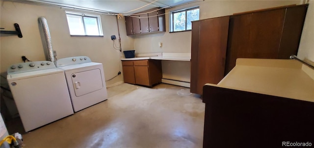 clothes washing area with washing machine and clothes dryer, baseboard heating, cabinet space, and a wealth of natural light