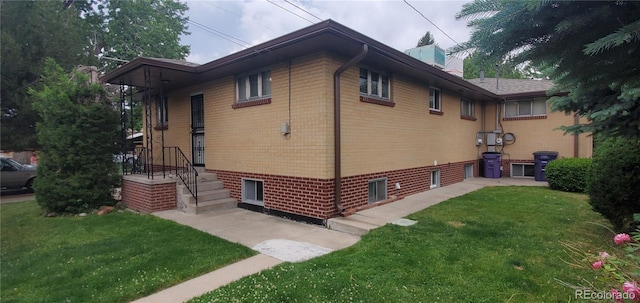 view of home's exterior featuring brick siding, a chimney, and a yard