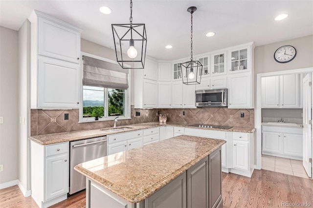 8993 Stonecrest Way, Highlands Ranch, CO 80129 - kitchen with stainless steel appliances, a sink, light wood finished floors, hanging light fixtures, and white cabinets