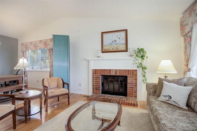 living room with lofted ceiling, a fireplace, and hardwood / wood-style floors