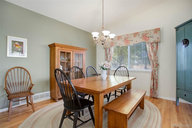 dining space with an inviting chandelier, light hardwood / wood-style flooring, and lofted ceiling