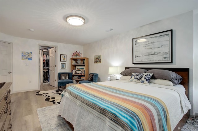 bedroom with a closet, a walk in closet, and light wood-type flooring