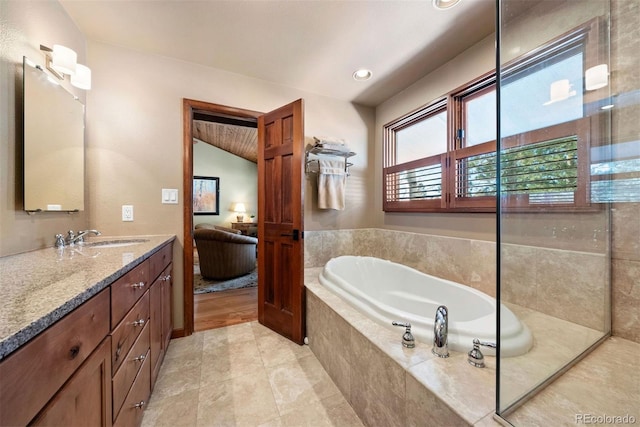 bathroom featuring vanity and tiled bath