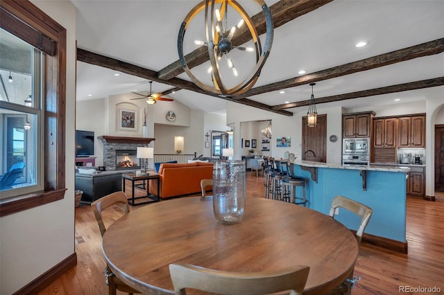 19336 Queens Crescent Way, Monument, CO 80132 - dining space featuring wood finished floors, a stone fireplace, a chandelier, a ceiling fan, and recessed lighting